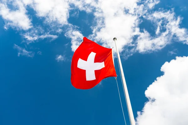 在风中向左转 瑞士国旗悬挂在桅杆上 背景是蓝天白云 — 图库照片