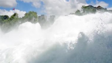 İsviçre bayrağı çırpınan arka planda akan, güçlü bir şelale, güzel bir görünüm. İsviçre'de Neuhausen Rheinfall nehri üzerinde Şelale Ren. Avrupa'nın en büyük şelalesi.