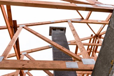 Yapım aşamasında müstakil bir evde sistem bacası, görünür baca bloğu ve çatı kirişlerinin elemanları.