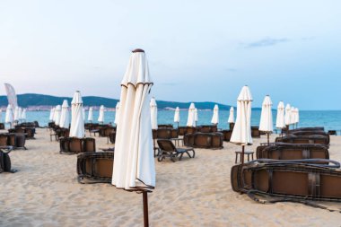 Bulgaristan'da Sunny Beach plajda şemsiye yanında yan yatan plaj şezlonglar, arka planda Karadeniz.