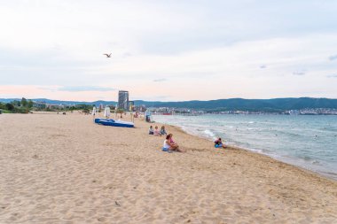 Sunny Beach, Bulgaristan 13 Temmuz 2019. Bulutlu bir günde gün batımından önce sahilde oturan birkaç turist.