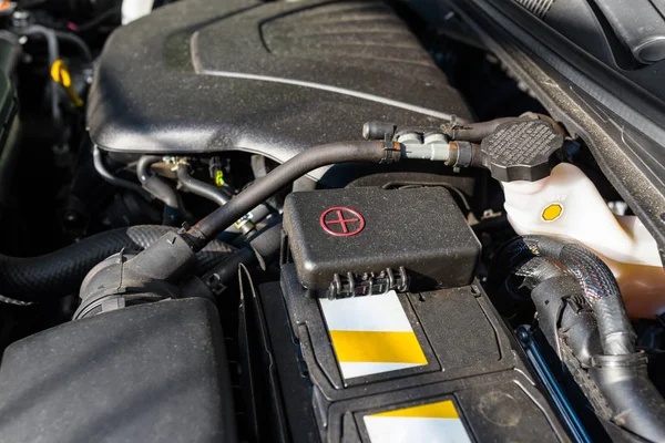 The plastic cover of the positive battery cell tip with the red plus symbol, the battery is placed in the engine compartment.