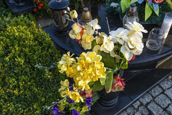 人工の花やろうそくは墓地の墓石に横たわっています — ストック写真
