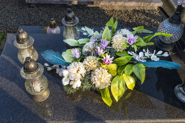 人工の花やろうそくは墓地の墓石に横たわっています — ストック写真