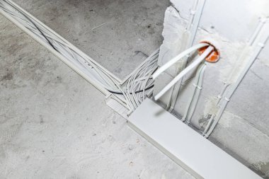 Yeni yapılmış bir evin zeminine elektrik kabloları döşemiş. Plastik tepsilerde duran kablolar.