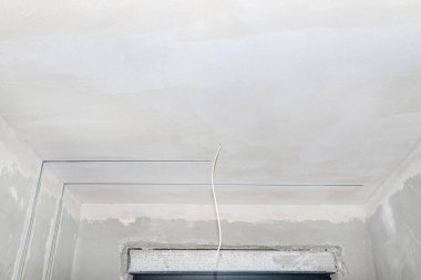 LED ışıklandırma için alüminyum profil yeni inşa edilmiş bir evin tavanına beton kireç alçıyla döşenmiş bir duvara yerleştirilmiş..