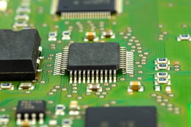 Yeşil devre kartındaki entegre devrenin makro fotoğrafı, görünür rezistanslar ve çip.