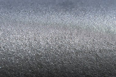 Güneş ışınlarıyla aydınlatılmış, seçici bir odak noktası olan metal bir yüzeyin makro görüntüsü..