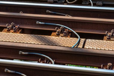 Demiryolu rayları nehrin üzerindeki demiryolu köprüsünde, ahşap yataklar üzerine uzanan topraklama kabloları ile birbirlerine bağlılar..