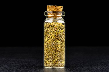 Siyah bir arka planda izole edilmiş mantarla kapalı küçük bir cam şişede otun makro görüntüsü..