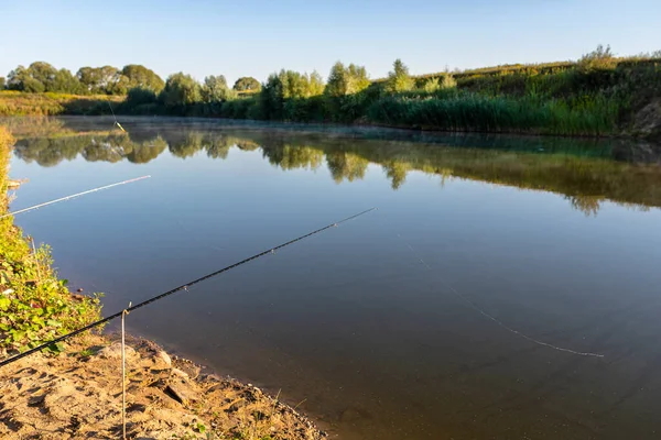 Due Canne Pesca Piedi Sulla Riva Sabbiosa Laghetto Illuminato Dal — Foto Stock