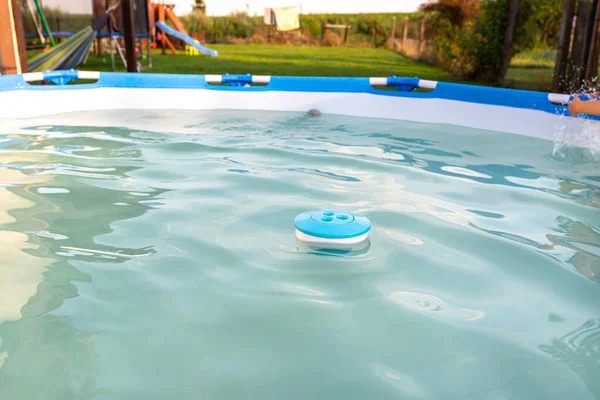 蓝色氯分配器漂浮在花园的家庭游泳池中 清洁和照料家庭游泳池 — 图库照片