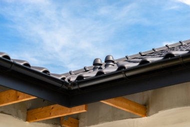 The roof of a single-family house covered with a new ceramic tile in anthracite against the blue sky, visible ceramic ventilation fireplace on the roof. clipart