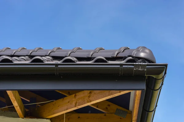 青い空 見える尾根のタイルに対するアントラサイトの新しいセラミックタイルで覆われた一戸建ての屋根 — ストック写真