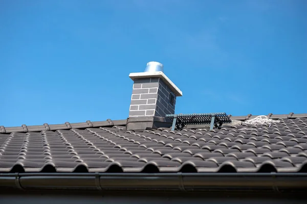 青い空に対するアントラサイトの新しいセラミックタイルで覆われた一戸建ての屋根 タイルで覆われた可視システム煙突 — ストック写真