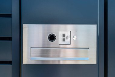 Posta kutusu ve kablosuz kart okuyucusu olan modern bir video fişi, antrakit renkli tel örgülere monte edilmiş..