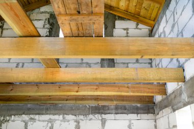 Tahta kirişler yeni yapılmış beyaz tuğla bir evin tavan arası döşemesi için hazırlandı..