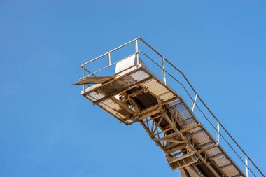 Endüstriyel çimento fabrikasında mavi gökyüzüne çakıl taşıma bandı.