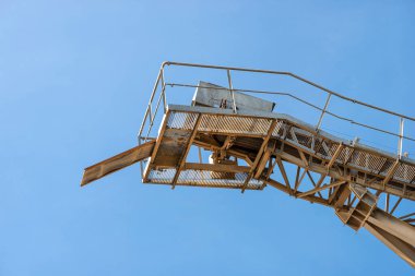 Endüstriyel çimento fabrikasında mavi gökyüzüne çakıl taşıma bandı.