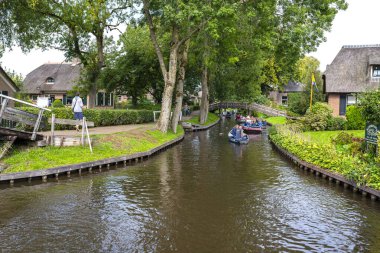 Giethoorn, Hollanda - 13 Eylül 2020. Ünlü Giethoorn köyünün evleri arasında kanalda tekne kiralayan turistler. Köye Hollanda 'nın Venedik' i denir..