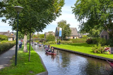 Giethoorn, Hollanda - 13 Eylül 2020. Ünlü Giethoorn köyünün evleri arasında kanalda tekne kiralayan turistler. Köye Hollanda 'nın Venedik' i denir..