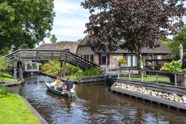 Giethoorn, Hollanda - 13 Eylül 2020. Ünlü Giethoorn köyünün evleri arasında kanalda tekne kiralayan turistler. Köye Hollanda 'nın Venedik' i denir..