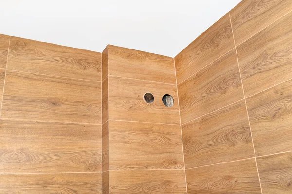 Modern gas boiler room with brown ceramic tiles imitating wood, empty room, visible holes of the ventilation chimney and gas exhaust.