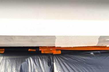 Pencere pervazında yeni uygulanan silikon alçı tabakası, pencere siyah folyoyla korunuyor.