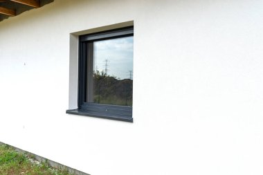 A newly applied layer of white silicone plaster on the wall of the house, visible window in anthracite. clipart