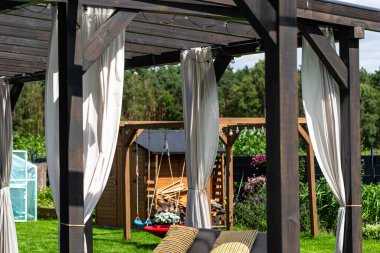 Evin arkasındaki teras görünür perdeleri ve dekoratif LED ışıkları olan kirişlerden yapılmıştır..