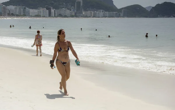 Bonita mujer caminando por la playa de Copacabana. Los ciudadanos se bañan — Foto de Stock