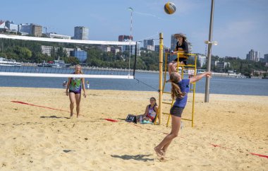  Sevimli kızlar plaj voleybolu oynar. Arkadaşlar oyunu izleyin.