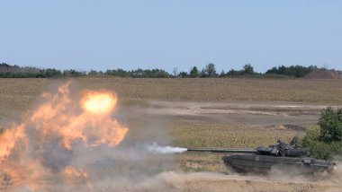 Tank bir top ateşler ve eğitim sahasında sıçrama tahtasından atlar.