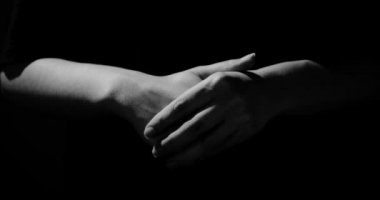 Eller siyah arka planda gergindir. Sakindirler, soyutlanmışlardır.