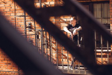 Adam dışarıda rahatlatıcı. Kıvırcık saçlı ofis, dışarıda seni bekleyen merdivenlerde oturan.