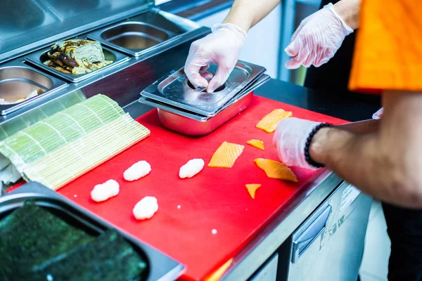 Japanese chef is neatly cutting on fine part of yellow fine tuna to make nigiri maguro sushi