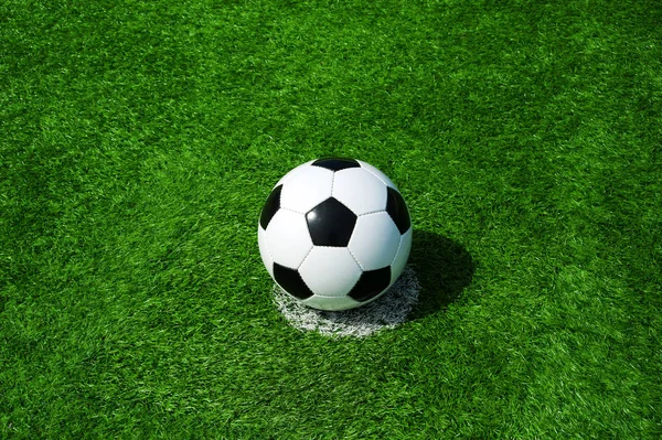 soccer ball classic in black and white on penalty spot on green artificial turf