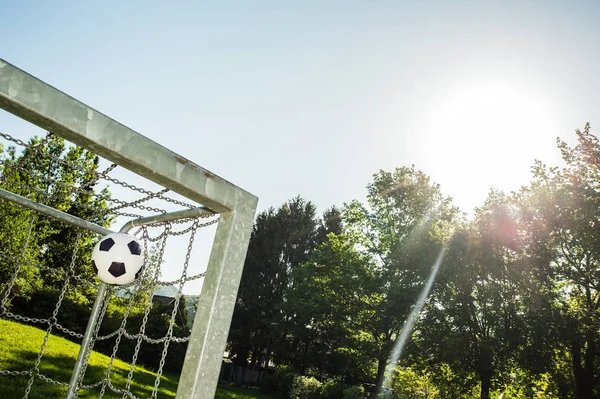 soccer ball in top corner of the goal in summer with sun and lensflare