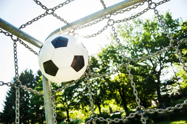 soccer ball in top corner of the goal in summer with sun and lensflare