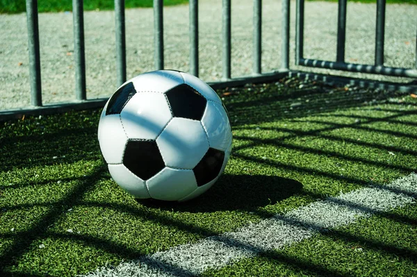 street soccer ball black and white on artificial ground with shadows stripes, on the line