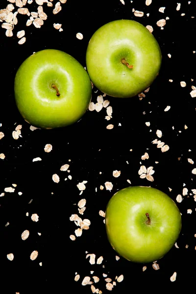 three green apples on black background