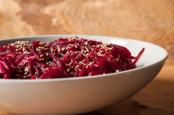 vegan cooking, beetroot with sesame in plate on wooden background