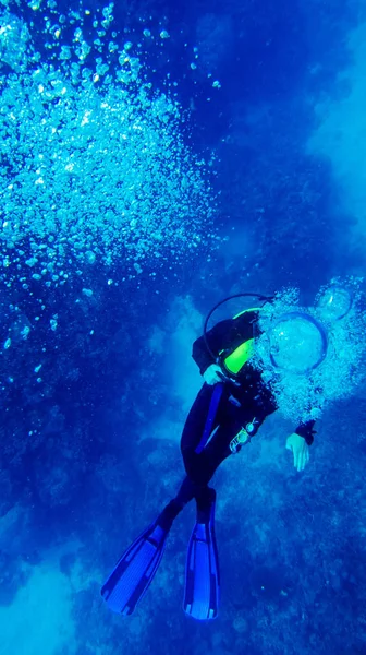 bir dalgıç koyu mavi su üzerinden hava kabarcıkları