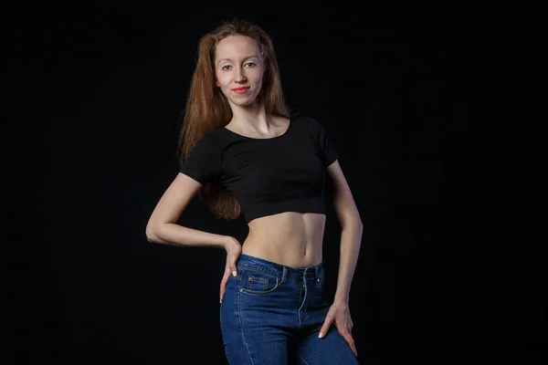 Güzel genç sportif kadın kameraya bir siyah arka plan üzerinde seyir