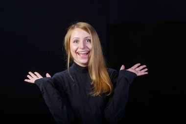 Siyah bir arka plan üzerinde gülüyor neşeli sarışın genç kadın