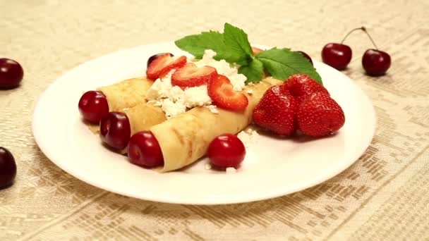 用草莓和樱桃馅的煎饼做成的甜点放在一个白色盘子里的桌子上 — 图库视频影像