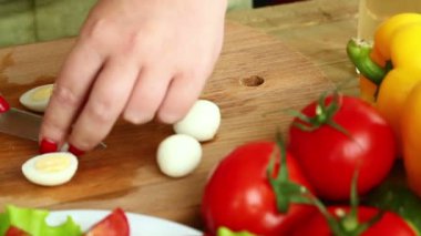 Hazırlık kiraz domates ile ev yapımı sebze salatası peynir ve Bıldırcın yumurta. Eller Bıldırcın yumurta bir bıçak ile kesmek. Kamera soldan sağa taşır.