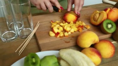Meyve kokteyli hazırlanması. Kadın bir şeftali bıçak düzenleyen bir kesme tahtası üzerinde. Kamera soldan sağa taşır.
