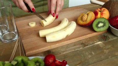 Kadın bir muz bıçak çalmak bir kesme tahtası üzerinde. Kamera soldan sağa taşır.