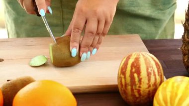 Vejetaryen diyet. Bir kadın bir bıçak bir kesme tahtası üzerinde olan bir kivi ile çalışıyor. Sağa soldan dolly ile Full Hd çekim.